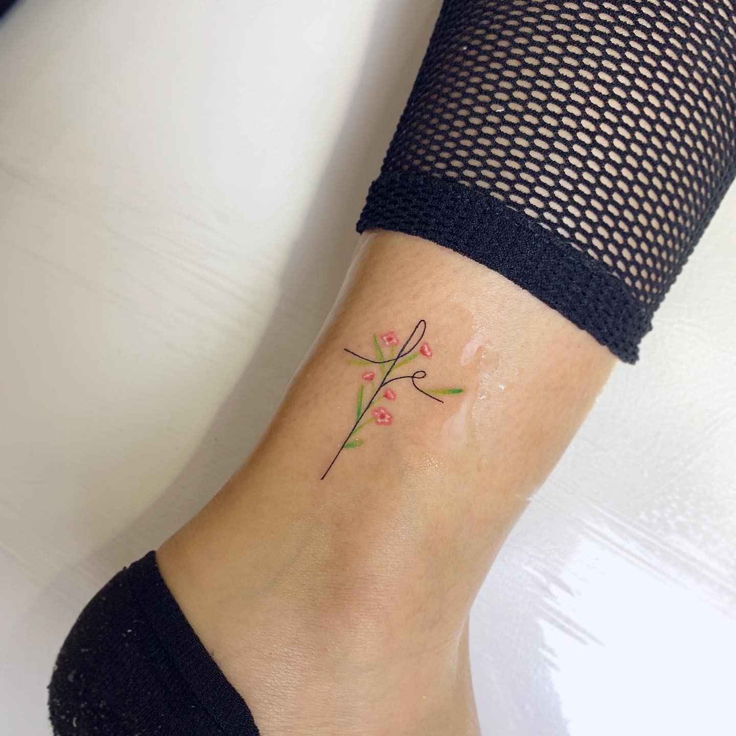 Delicate ‘Fe’ Cross Tattoo with Flowers