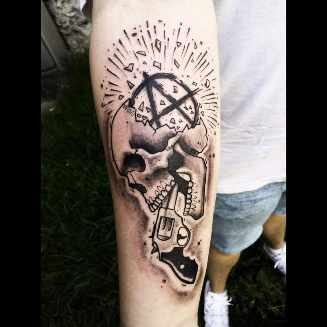 Amazing Black And Gray Pistol Shooting Skull Anarchism Tattoo Idea For Forearm