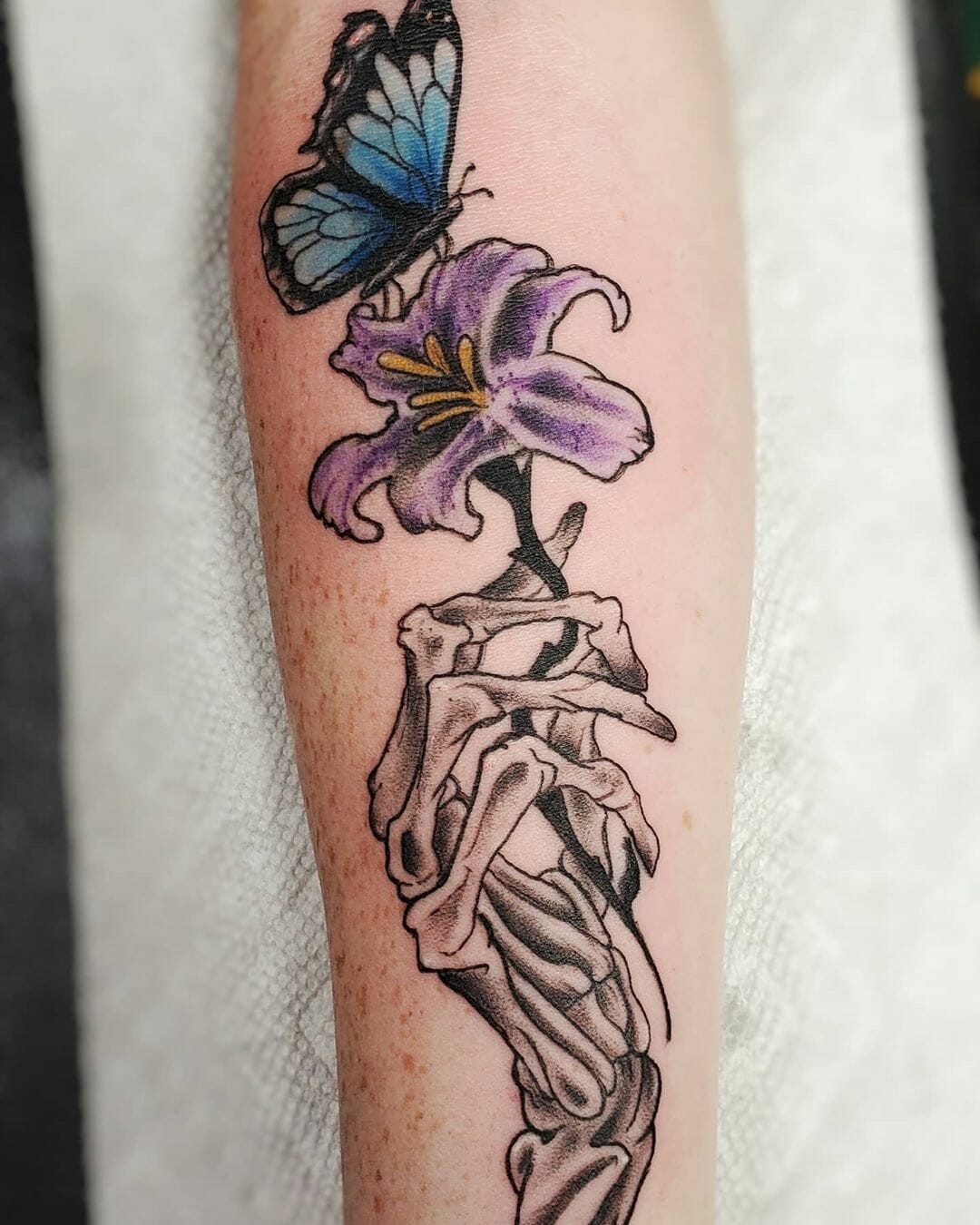 Skeleton Hand Holding Butterfly and Iris Tattoo