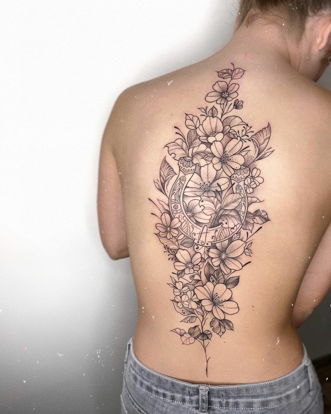 Black Ink Outlines Horseshoe With Flowers Tattoo Incredibly Detailed Design On Back